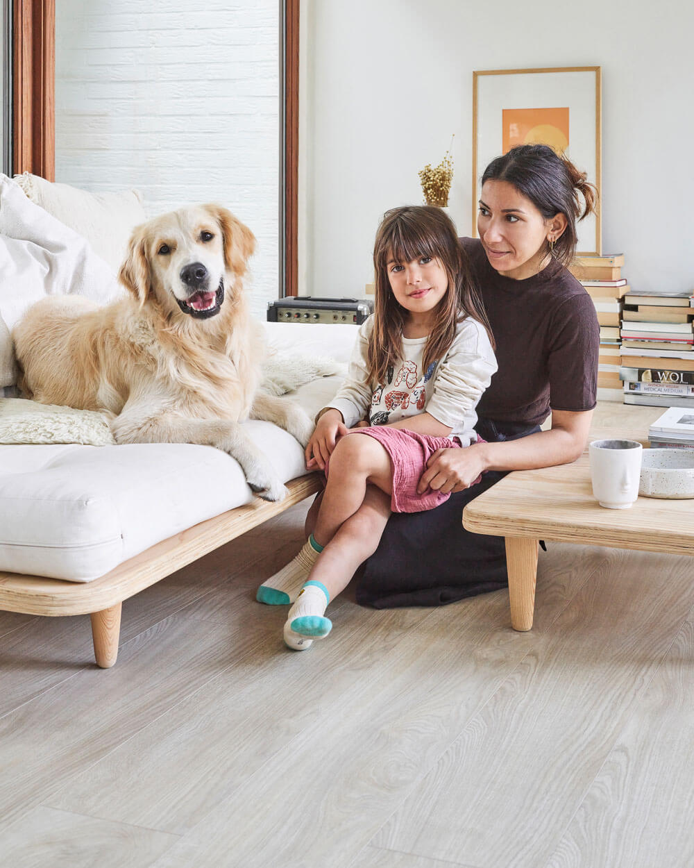 Sumeyya zit met haar dochter op de vloer in de woonkamer. Het gaat om de Moduleo LayRed Laurel Oak 51230 Embossed luxe pvc vloer.